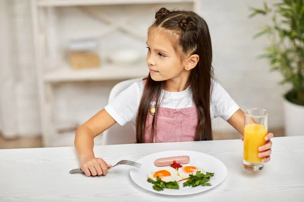 Маленькая девочка завтракает - яичница и апельсиновый сок — стоковое фото