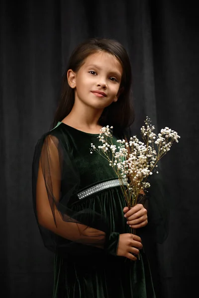 Маленька дівчинка в зеленій сукні тримає квіти — стокове фото