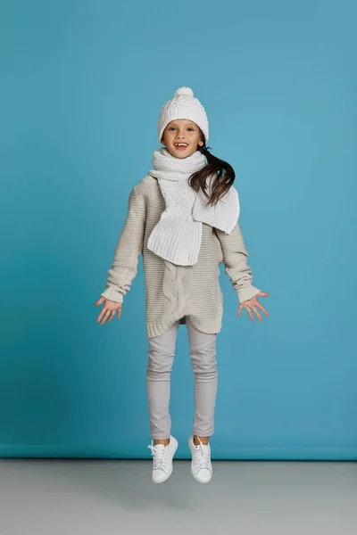 겨울에 여자 아이가 모자에 스웨터를 입고 점프하는 모습 — 스톡 사진