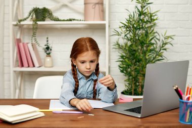 Küçük kız çevrimiçi çalışmak için laptop kullanıyor.