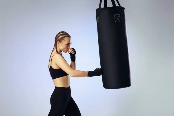 Mujer morena deportiva con vendaje de boxeo compartiendo la bolsa de boxeo — Foto de Stock