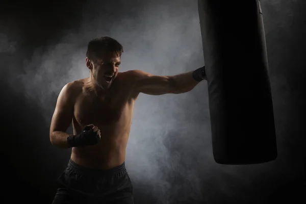 Boxeador en boxeo negro envuelve perforación en bolsa de boxeo — Foto de Stock