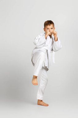 Beyaz karate kimonosu giymiş bir çocuk.