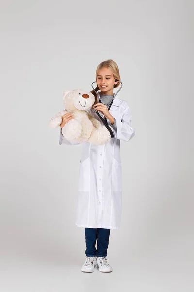 Bambino carino in cappotto medico con stetoscopio — Foto Stock