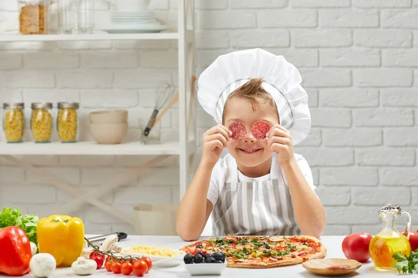 Kleiner Junge mit Kochmütze und Schürze beim Pizzakochen — Stockfoto