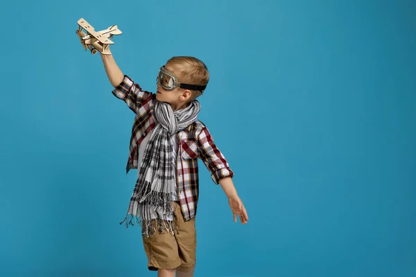 Barn pojke i retro glasögon leka med trä leksak flygplan — Stockfoto