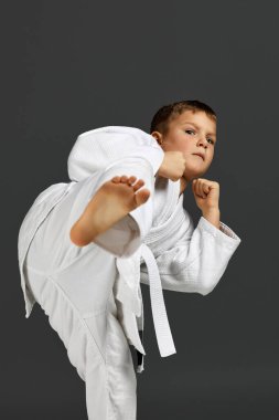 Beyaz karate kimonosu giymiş bir çocuk.