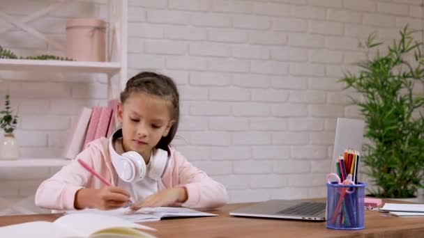 Klein kind meisje met behulp van laptop voor het doen van schooltaken thuis en het schrijven van notities. — Stockvideo