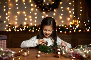 Küçük kız el yapımı Noel çelengi yapıyor.