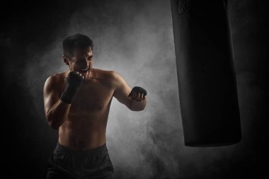 Siyah boksör boks çantasını yumrukluyor.