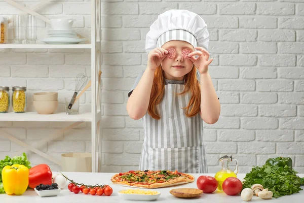 Kleines Mädchen mit Kochmütze und Schürze beim Pizzakochen — Stockfoto