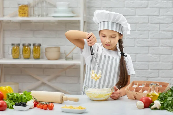 Kleines Mädchen knetet mit Krönchen den Teig — Stockfoto