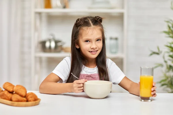 Мила маленька дівчинка сніданок - крупа та апельсиновий сік — стокове фото