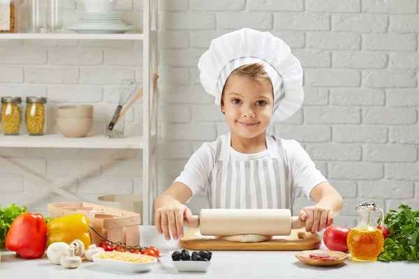 Menino pequeno em boné e um avental cozinheiro — Fotografia de Stock