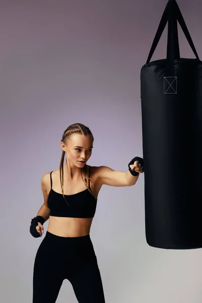 Mujer morena deportiva con vendaje de boxeo compartiendo la bolsa de boxeo —  Fotos de Stock