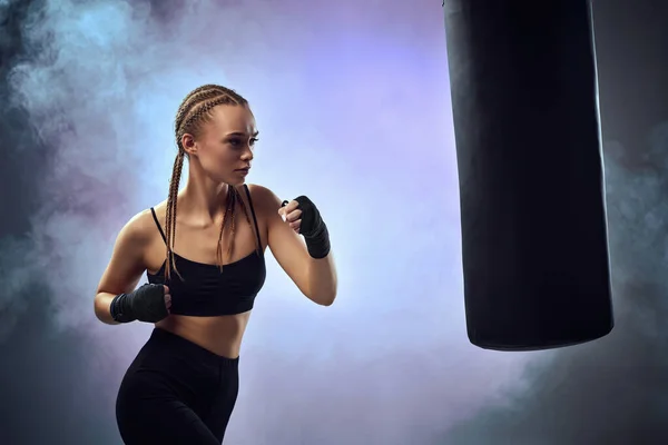 Mulher com bandagens de boxe batendo o saco de boxe — Fotografia de Stock