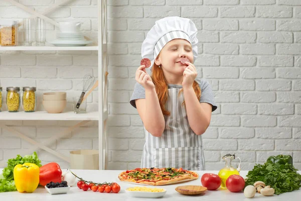 Kislány séf kalapban és kötény főzés pizza — Stock Fotó