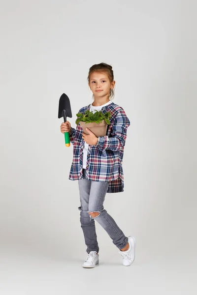 Маленька дівчинка поливає рослини в квітковому горщику — стокове фото