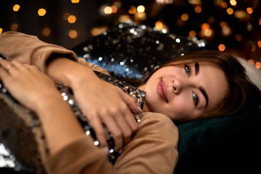 Uzun saçlı güzel genç bir kadın yatakta yatıyor.