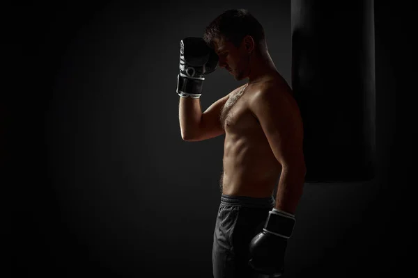 Boxeador en guantes negros de pie cerca del saco de boxeo — Foto de Stock
