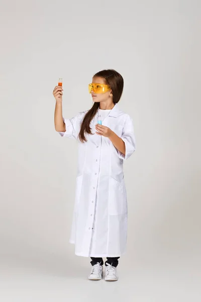 Маленька дівчинка тримає хімічну колбу і пробірку — стокове фото