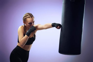 Boks bandajlı kadın boks çantasına vurdu.