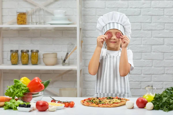 Kislány séf kalapban és kötény főzés pizza — Stock Fotó