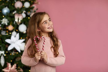 Sevimli küçük kız elinde lolipop şeker kamışı tutuyor.