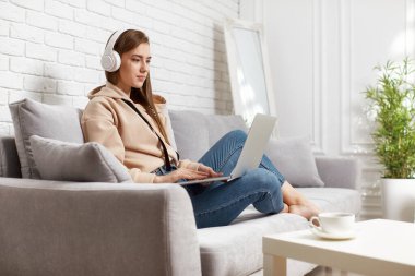 Evde dizüstü bilgisayar kullanan genç bir kadın.