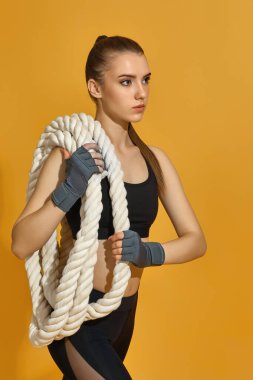 Ağır iplerle siyah spor kıyafetli bir kadın.