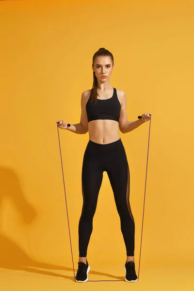 Mulher em sportswear preto com corda de salto — Fotografia de Stock