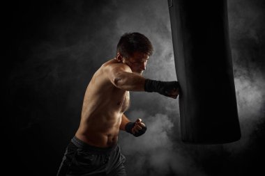 Siyah boksör boks çantasını yumrukluyor.