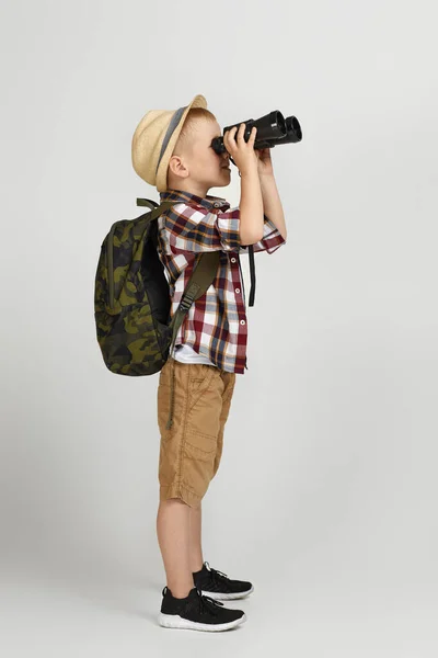 Liten pojke turist med ryggsäck tittar igenom en kikare. — Stockfoto