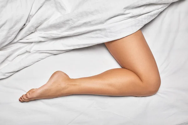 Bela perna feminina com roupa de cama branca — Fotografia de Stock