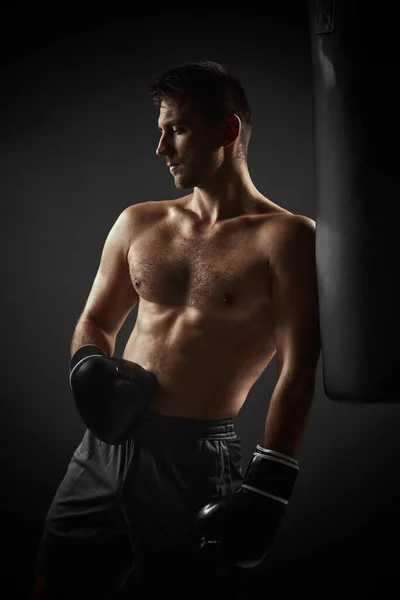 Боксер в чорних рукавичках, що стоять біля мішка для удару — стокове фото