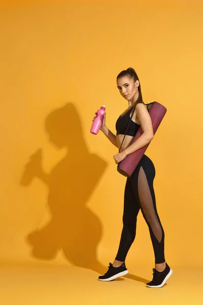 Mujer en ropa deportiva negra sosteniendo una botella de agua —  Fotos de Stock