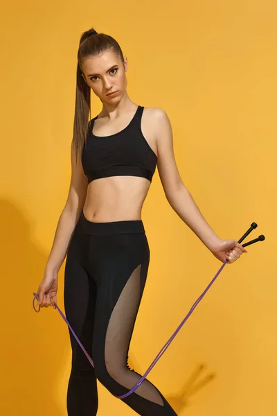 Mulher em sportswear preto com corda de salto — Fotografia de Stock