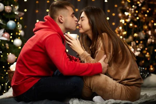 Любящая пара целуется на рождественской елке — стоковое фото