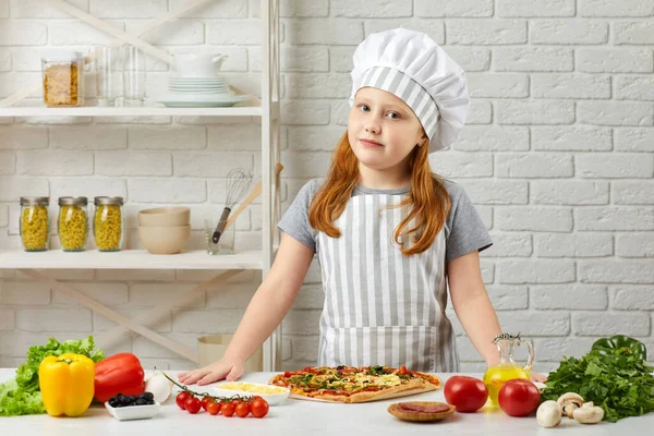 Kleines Mädchen mit Kochmütze und Schürze beim Pizzakochen — Stockfoto