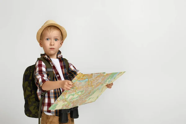 Liten pojke turist med ryggsäck innehav kikare och karta. — Stockfoto