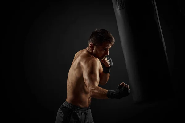 Boxeador masculino perforando en bolsa de boxeo — Foto de Stock