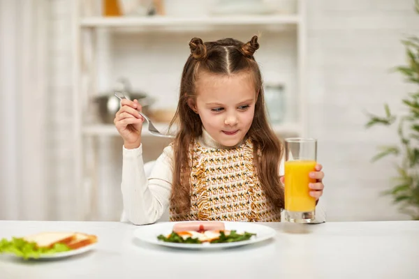 Маленька дівчинка снідає - смажене яйце та апельсиновий сік — стокове фото