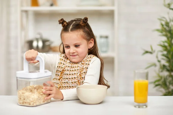 Мила дівчинка їсть сніданок: крупа та апельсиновий сік — стокове фото