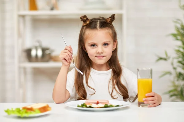 Маленькая девочка завтракает - яичница и апельсиновый сок — стоковое фото