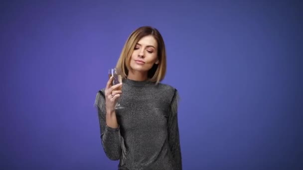 Woman in silver shirt holding glass of champagne and smiling — Stock Video