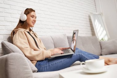 Evde dizüstü bilgisayar kullanan genç bir kadın.