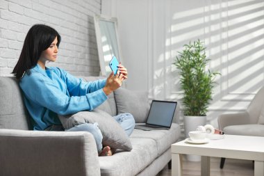 Evde akıllı telefon kullanan bir kadın..