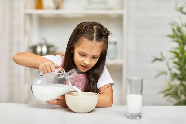 Мила дівчинка їсть сніданок: крупа з молоком — стокове фото