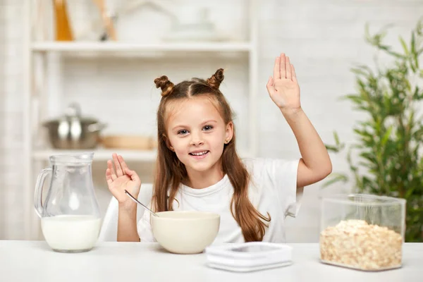 Маленька дівчинка їсть сніданок: крупа з молоком на кухні . — стокове фото