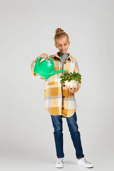 Bambina che annaffia piante in un vaso di fiori — Foto Stock